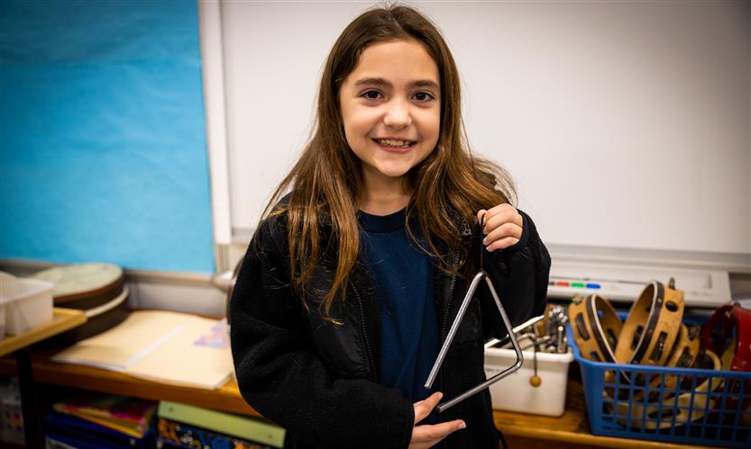 A girl smiles while holding an instrument